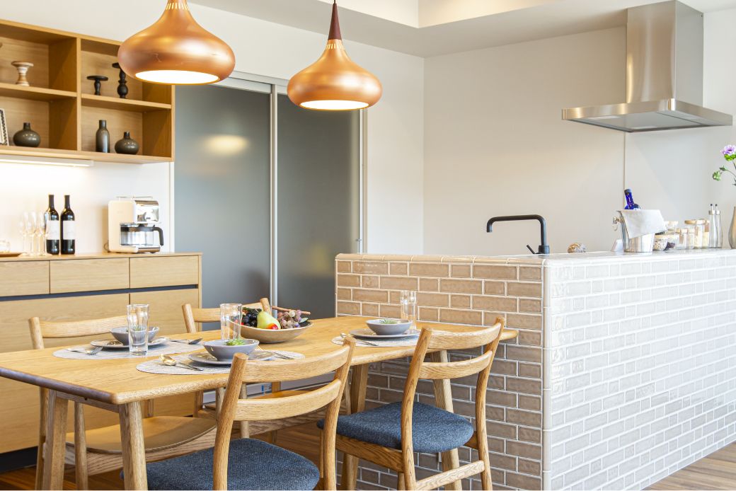 キッチンにいる母親とテーブルについている父親と子供達が笑い合う様子